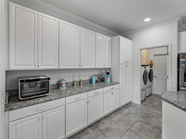 kitchen featuring separate washer and dryer, white cabinetry, ornamental molding, and dark stone countertops