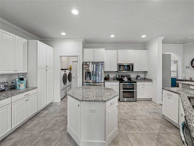 kitchen featuring light stone counters, appliances with stainless steel finishes, washer and clothes dryer, and a kitchen island