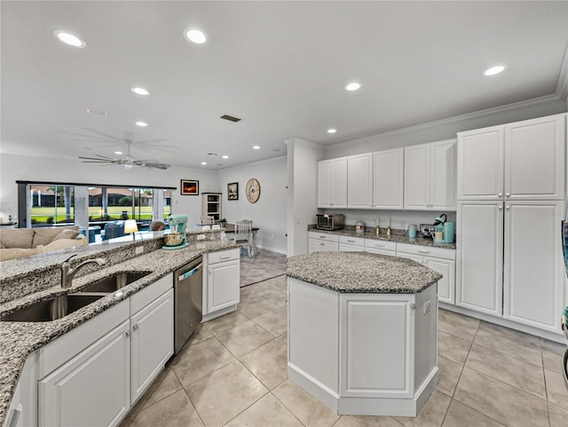 kitchen with sink, white cabinetry, light stone counters, stainless steel dishwasher, and a kitchen island