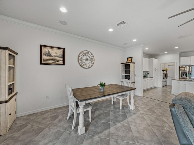 dining area with light tile patterned floors, crown molding, and washer and clothes dryer