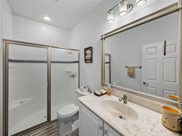 bathroom featuring vanity, a shower with shower door, and toilet