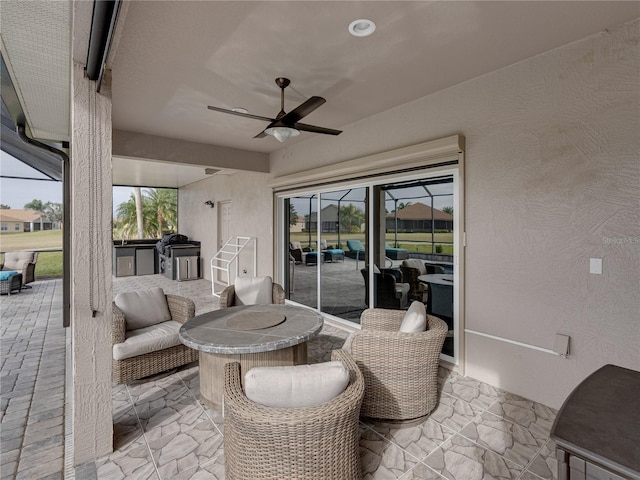 view of patio / terrace featuring an outdoor hangout area, ceiling fan, and glass enclosure