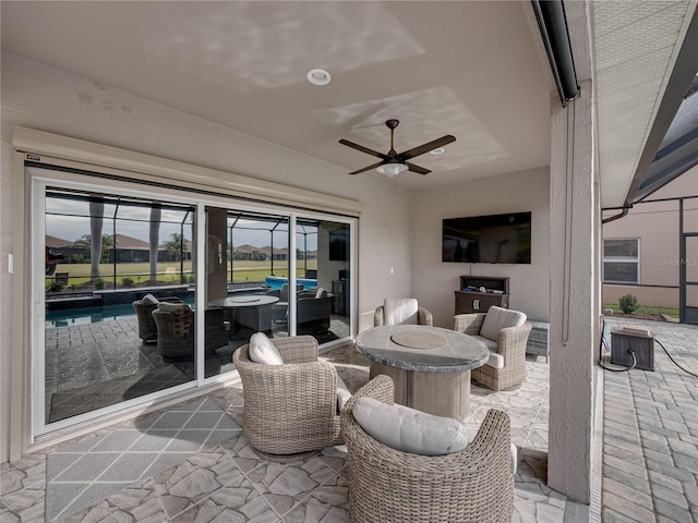 view of patio featuring ceiling fan and glass enclosure