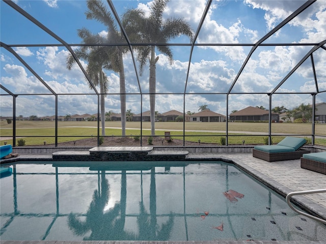 view of pool featuring a patio, glass enclosure, and a lawn