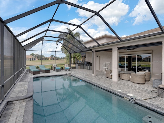 view of pool with ceiling fan, a patio, outdoor lounge area, and glass enclosure