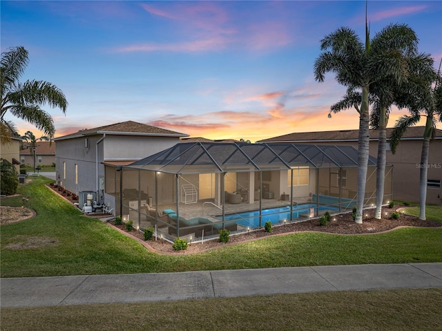 pool at dusk featuring cooling unit, a lanai, and a lawn