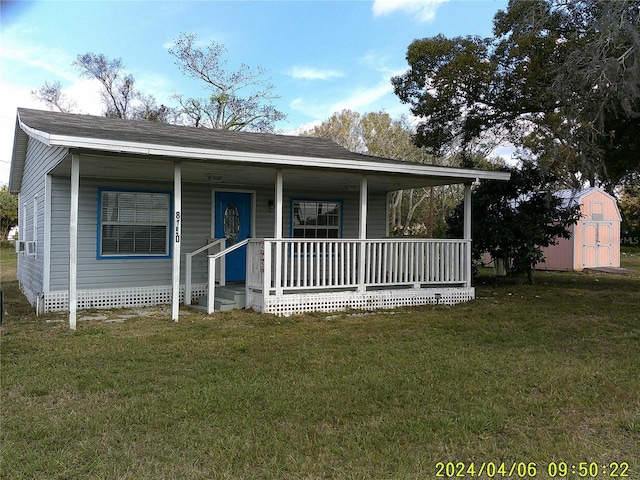 view of front facade featuring a storage unit, covered porch, and a front yard