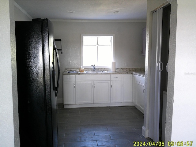 kitchen featuring black refrigerator, ornamental molding, sink, and white cabinets