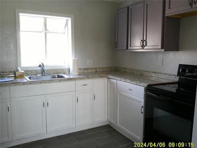 kitchen with white cabinets, sink, and electric range