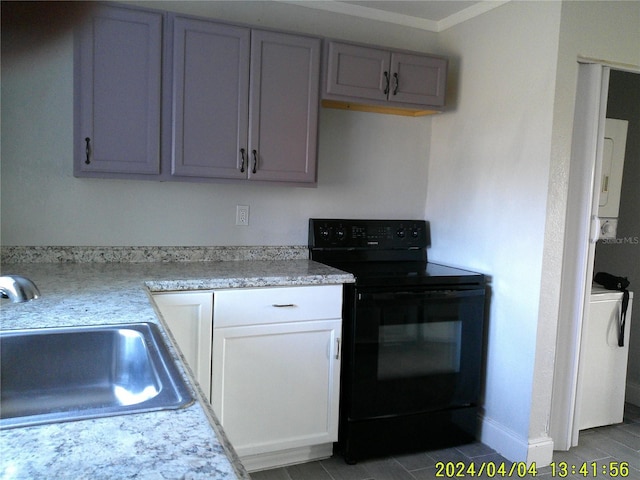 kitchen featuring sink, stacked washer and dryer, gray cabinetry, black range with electric cooktop, and tile patterned floors