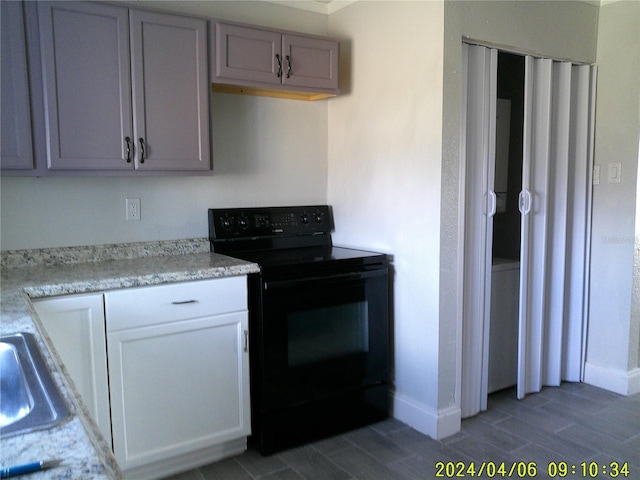 kitchen with black range with electric stovetop and light stone counters