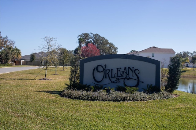 community sign with a lawn and a water view