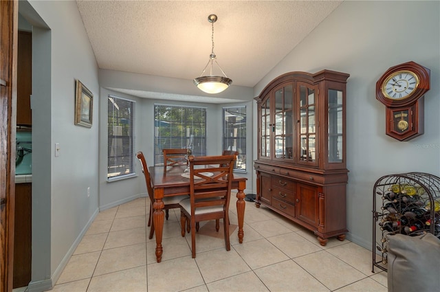 tiled dining space featuring lofted ceiling and a textured ceiling