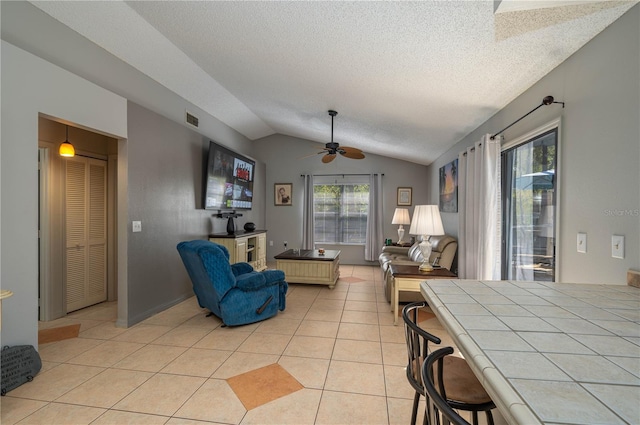 living room with light tile patterned flooring, ceiling fan, vaulted ceiling, and a textured ceiling