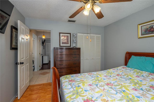 bedroom featuring ceiling fan, a textured ceiling, light hardwood / wood-style floors, and a closet