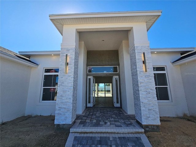 view of exterior entry with stone siding and stucco siding