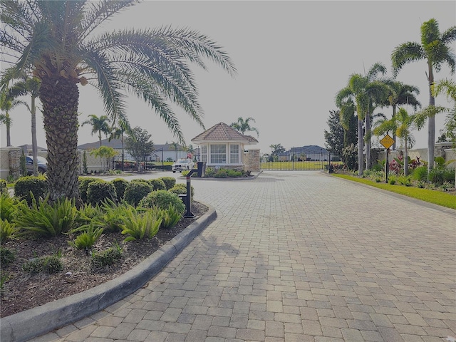 view of road with curbs, a gated entry, traffic signs, and a residential view