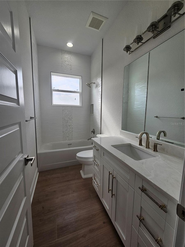 full bathroom featuring visible vents, toilet, washtub / shower combination, vanity, and wood finished floors