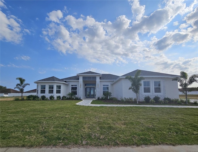 prairie-style house featuring stucco siding, french doors, and a front yard