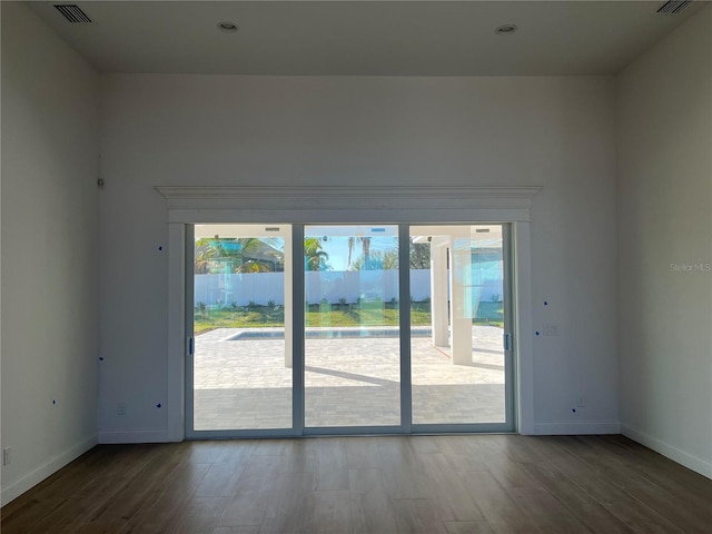 doorway featuring visible vents, baseboards, and wood finished floors