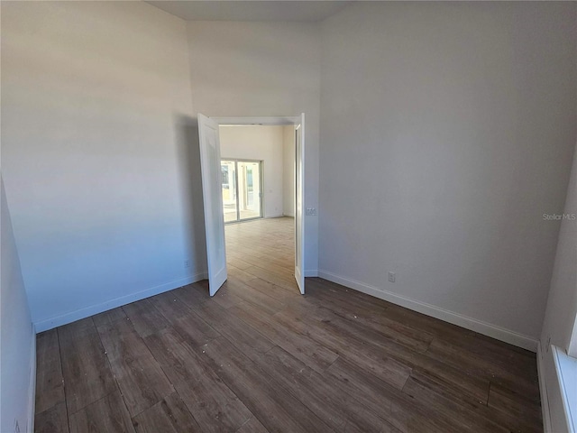 spare room with baseboards and dark wood-type flooring