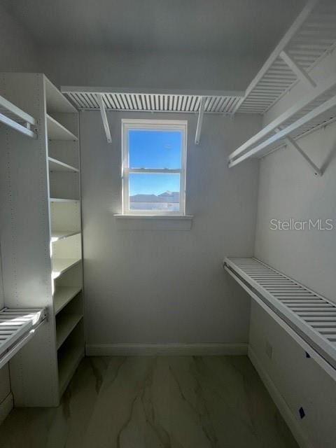 walk in closet featuring marble finish floor