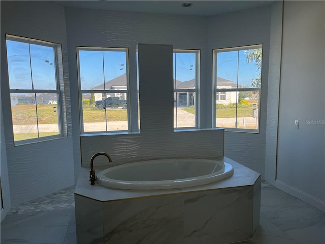 bathroom featuring marble finish floor and a bath