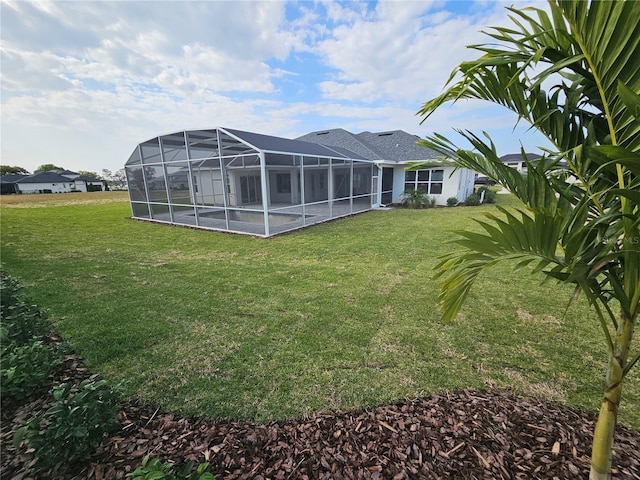 rear view of house featuring glass enclosure, stucco siding, and a yard