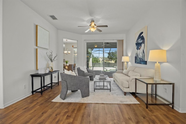 living room with ceiling fan with notable chandelier and hardwood / wood-style floors