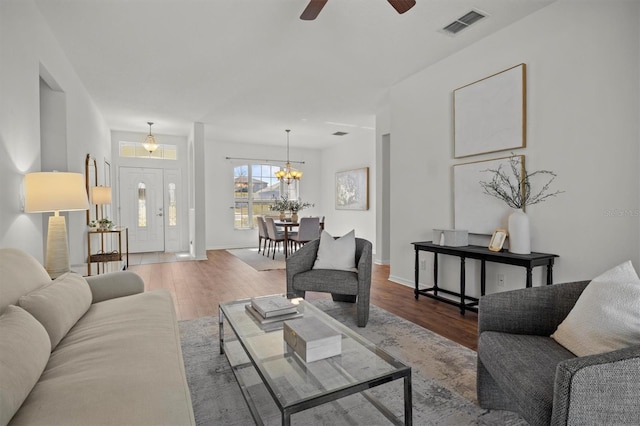 living room with ceiling fan with notable chandelier and hardwood / wood-style floors