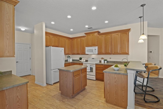 kitchen with a breakfast bar, pendant lighting, light hardwood / wood-style floors, kitchen peninsula, and white appliances