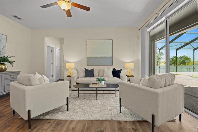 living room featuring wood-type flooring, a water view, a textured ceiling, and ceiling fan