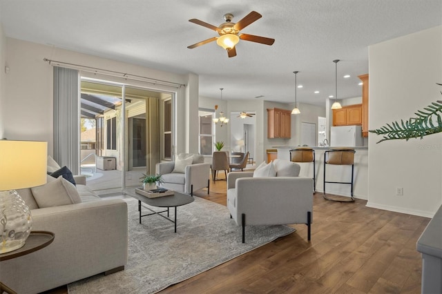 living room with hardwood / wood-style flooring, a textured ceiling, and ceiling fan