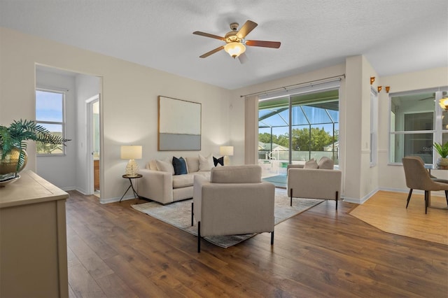 living room featuring dark hardwood / wood-style flooring, a textured ceiling, and ceiling fan