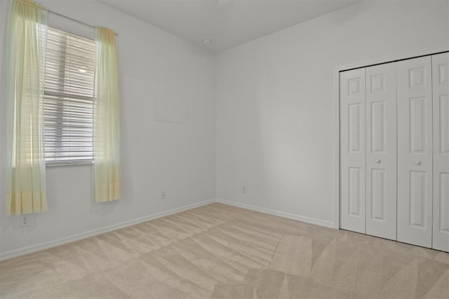 unfurnished bedroom with light colored carpet and a closet