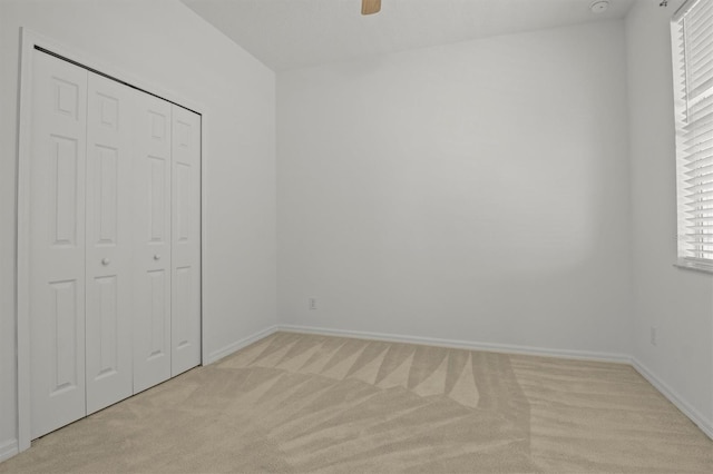 unfurnished bedroom with light colored carpet, ceiling fan, and a closet