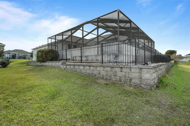 exterior space featuring glass enclosure and a lawn