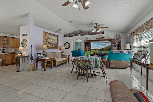 tiled dining room featuring ceiling fan, lofted ceiling, and a textured ceiling