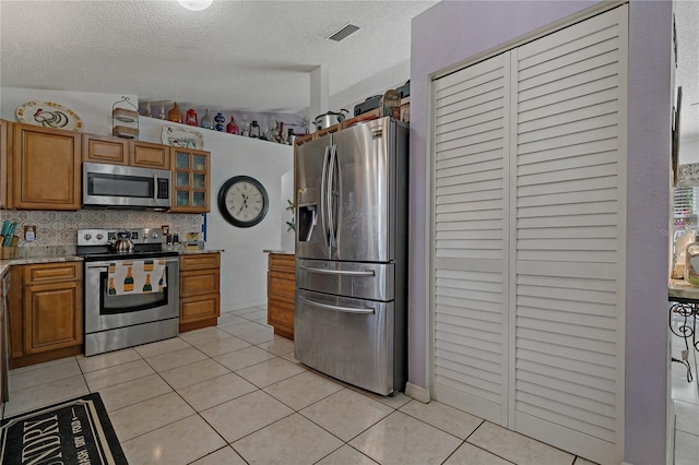 kitchen featuring tasteful backsplash, stainless steel appliances, a textured ceiling, and light tile patterned flooring