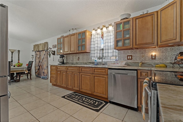 kitchen with sink, appliances with stainless steel finishes, tasteful backsplash, a textured ceiling, and light tile patterned flooring