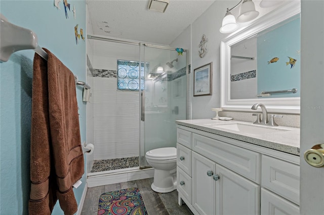 bathroom with vanity, an enclosed shower, wood-type flooring, a textured ceiling, and toilet