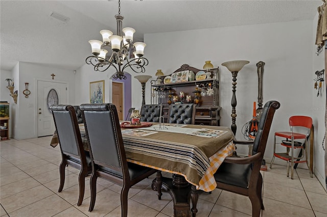 tiled dining area featuring an inviting chandelier and a textured ceiling