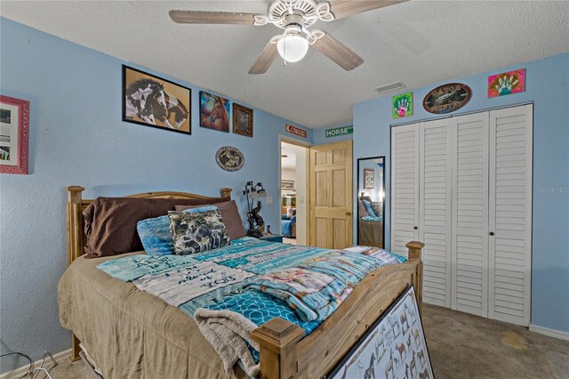 carpeted bedroom with ceiling fan, a closet, and a textured ceiling