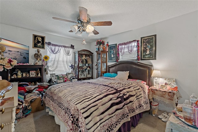 carpeted bedroom featuring ceiling fan and a textured ceiling