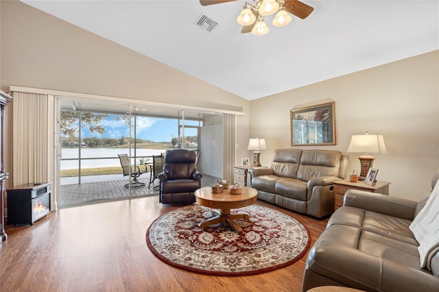 living room featuring hardwood / wood-style flooring, vaulted ceiling, ceiling fan, and a water view