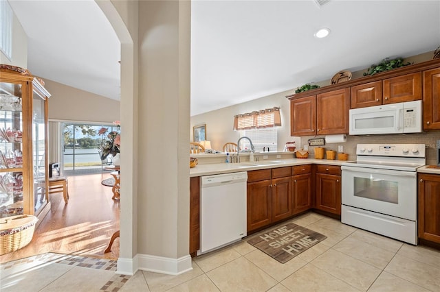 kitchen featuring vaulted ceiling, sink, light tile patterned floors, and white appliances