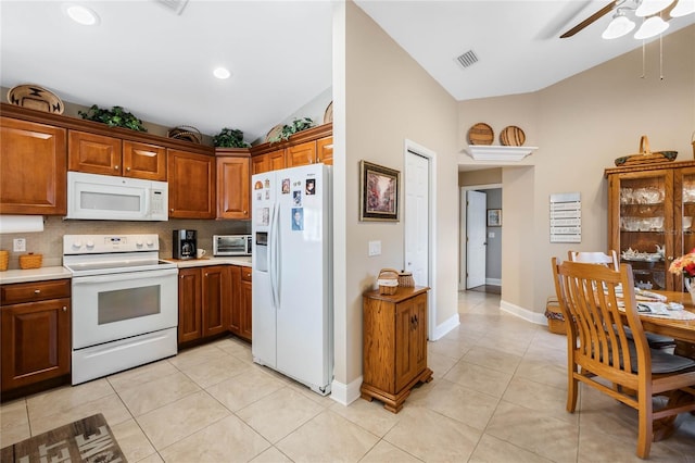 kitchen with light tile patterned floors, white appliances, ceiling fan, backsplash, and vaulted ceiling