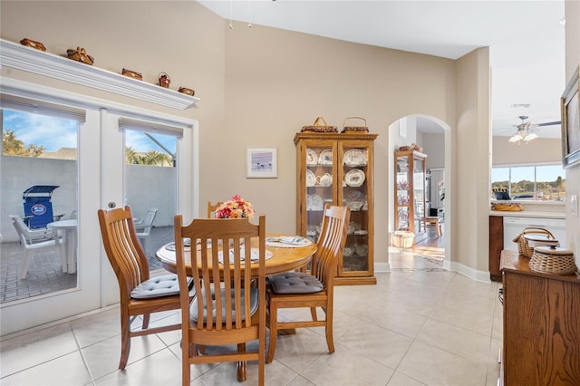 tiled dining area featuring a towering ceiling, a healthy amount of sunlight, and french doors