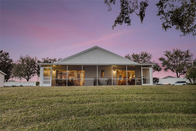 back house at dusk with a lawn