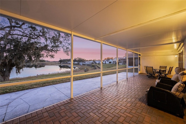 sunroom featuring a water view